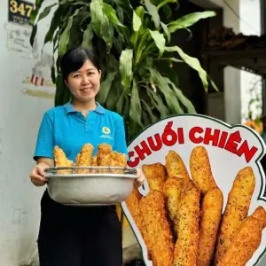Cô Minh bưng mẹt bánh chuối chiên trước quán